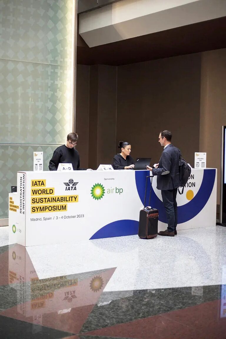 Persona acercándose al mostrador de cartón para realizar el check-in en el evento