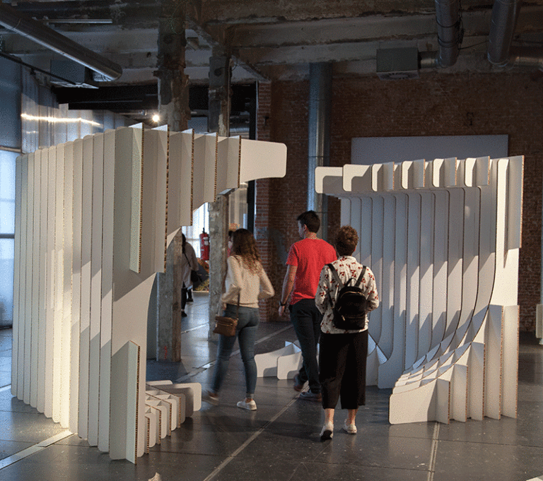 Personas caminando por un túnel paramétrico de cartón en un evento sostenible en Matadero