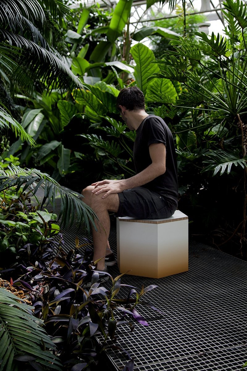 Persona sentada sobre un taburete de cartón en un entorno natural. Diseño ecológico para eventos.