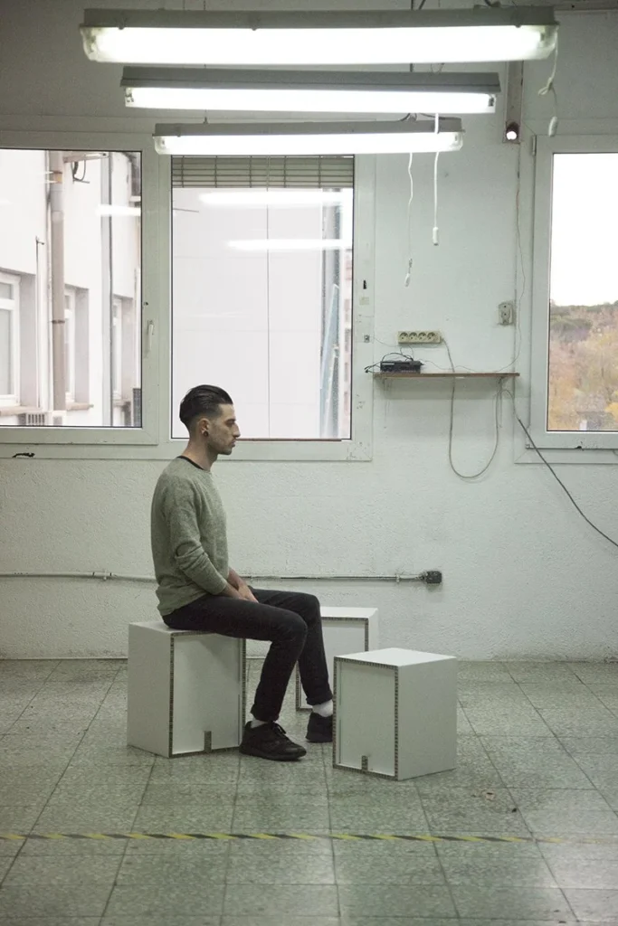 Persona sentada de perfil sobre un taburete de cartón para eventos