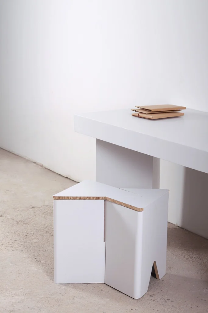 Taburete de cartón impreso INFIX en blanco liso junto a mesa de cartón en ambiente minimalista