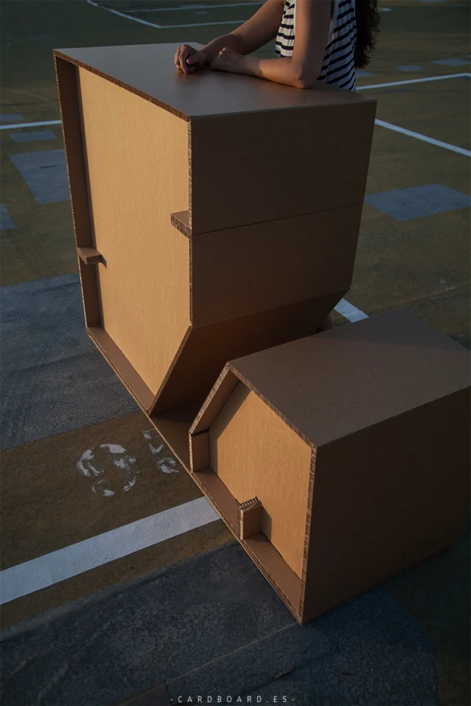 Mostrador de cartón Dos Alturas de Cardboard en ambiente exterior interactivo, destacando su estructura geométrica y resistente.