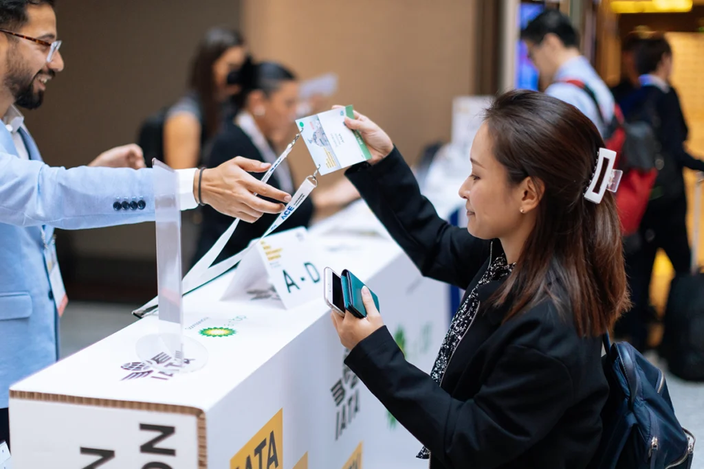 Persona interactuando con el personal detrás del mostrador de cartón en la recepción del evento