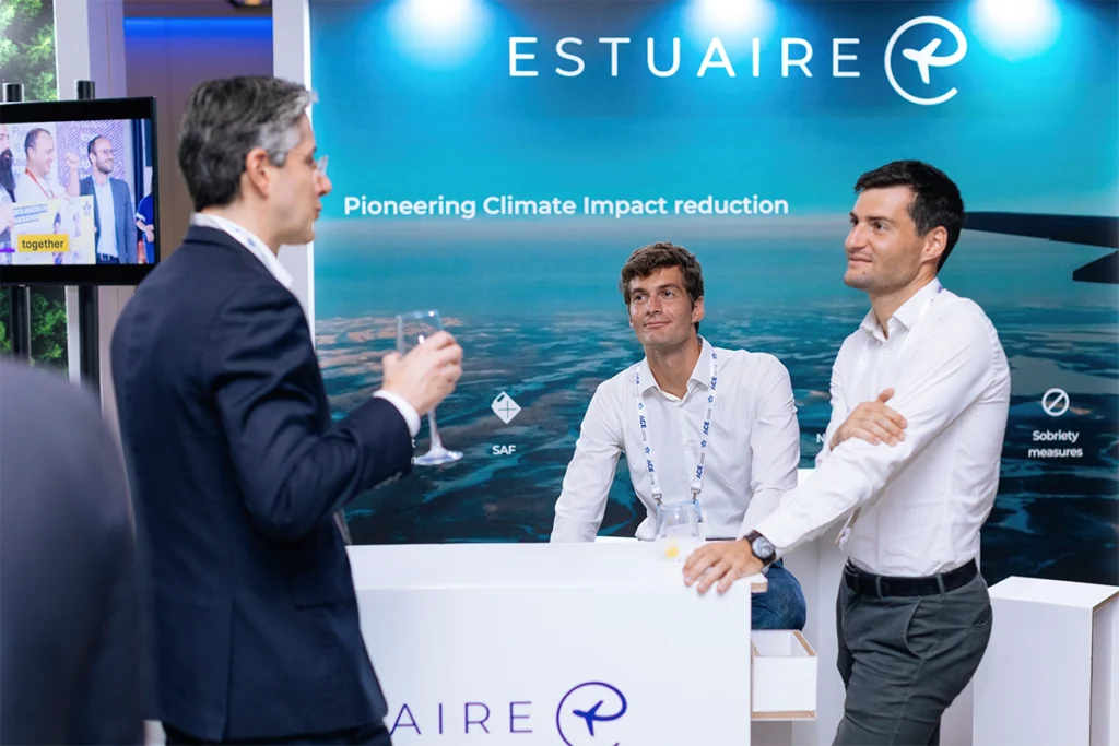 Personas conversando junto al mostrador de cartón en uno de los stands del evento IATA