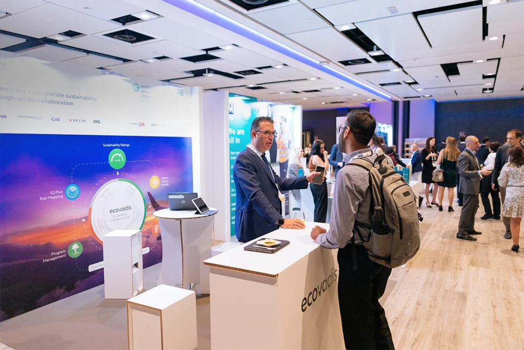 Personas interactuando en un stand sostenible de cartón durante el evento IATA